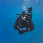 Underwater view of a scuba diver exploring the ocean depths, surrounded by a tranquil blue ambiance.