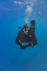 Underwater view of a scuba diver exploring the ocean depths, surrounded by a tranquil blue ambiance.